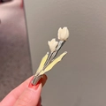 Hand holding white and yellow enamel tulip hair clip with silver metal base - Beige