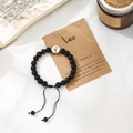 Detail of Leo zodiac handmade braided bracelet with black beads on descriptive card - Leo