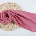 Pink chiffon hijab scarf elegantly styled as a rose on a natural woven mat - 102