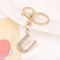 Macro view of gold-plated metal letter U keychain encrusted with clear rhinestones - Letter U