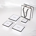 White jewelry gift box set with black trim and matching paper bags in various sizes - White