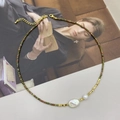 Detail van barokparel en toermalijn kralenketting op een vintage poster achtergrond - Unakiet