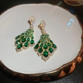 Macro detail of leaf-shaped gold earrings with emerald green crystals and white zircon accents - Silver Earring Post-Green