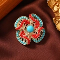 Makroaufnahme einer Retro-Blumenbrosche mit türkisfarbenen Perlen und Goldbasis - Künstliche Türkis Friedensknoten-Bunt Gemischt