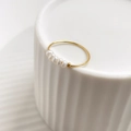 Macro detail of French style gold ring with five white pearls on white ceramic base - US Size 3 / Pearl Style