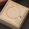 Goldenes Hamsa-Hand Armband mit blauem Auge und Kristallen auf einer Schmuckbox - Hamsa Hand Böser Blick Armband