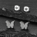 Glitzernde Schmetterling-Ohrstecker in Silber auf schwarzem Steinhintergrund - Stahlschmetterling