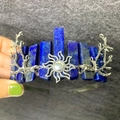 Detail der Krone aus blauem Lapislazuli mit silbernem Sonnenanhänger in der Hand - Lapislazuli + Sonne + Ast