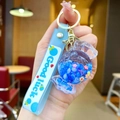 Close-up of candy-shaped keychain with blue liquid, flowers and Good Luck wristlet - Lollipop String [blue] Glow-in-the-dark Bubble Bead Candy