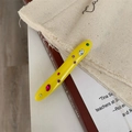 Close-up of yellow irregular acrylic hair clip with colorful crystals on a burgundy book - Yellow Rhinestone Hair Clip