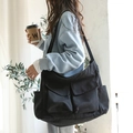 Black canvas messenger bag featuring dual front pockets and large storage capacity - Black