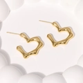 Detailed view of gold wave-patterned heart stud earrings on a white relief surface - Lava Heart Style (ER012) / Gold