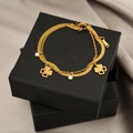Detail of gold titanium bracelet featuring double chains with clover and crystal charms - Hollow Four-leaf Clover Double Layer Style (SL-51)