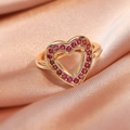 Macro view of gold heart ring featuring pave-set red gemstones on peach satin - Large Red Heart/Gold Hollow