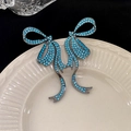 Bow brooch with light blue rhinestones on dark metal base displayed on a ceramic plate - 68# Silver Earring Post-Blue Bow