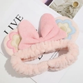 Gros plan du bandeau en peluche rose avec noeud brodé de fleurs et texture douce en polaire - Rose