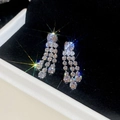 Dettaglio di orecchini ad ago in argento con catene di zirconi e riflessi scintillanti - Argento