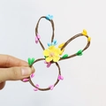 Detail eines gewebten Osterhasen-Serviettenrings aus Rattan mit bunten Tropfen und Blume - Gelbes Blumenmuster