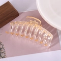 Close-up of a large amber-toned transparent plastic hair claw clip with a hollow bone structure - Glossy Transparent Champagne 11cm