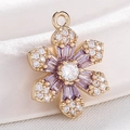 Golden flower pendant with purple zircon stones on a soft white fabric background - S116-06 Gold Purple White Zircon Flower
