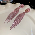 Dettaglio macro di orecchini nappa con strass rosa scintillanti su un piatto a conchiglia - Perno per orecchini in argento - Rosa