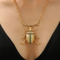 Dettaglio di una collana scarabeo vintage con pietre verdi su pendente dorato - Collana Scarabeo (1974)