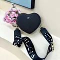 Detail of black heart-shaped crossbody bag with gold hardware and wide pattern strap - Black