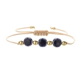Close-up of adjustable woven cord bracelet with blue ceramic flowers and gold beads - Copper Beads + Royal Blue Flowers