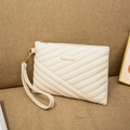 Detail of cream quilted handbag featuring gold metal plaque and detachable wrist strap - White