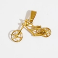 Dettaglio ravvicinato di un ciondolo a forma di moto dorata con finitura in metallo traforato - Oro