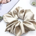 Detailansicht eines champagnerfarbenen Satin-Haargummis auf weißem Tisch mit Deko - 20cm / Champagnergold