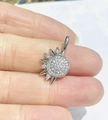 Vista macro dettagliata di un ciondolo a sole in argento con zirconi tenuto su un dito - Sole Pavé Argento