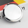 Close-up of a round silver metal compact mirror showing side hinge and push-button lock - Solid Bottom / Silver