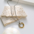 Dreiring-Halskette mit ineinandergreifenden Ringen in Silber und Gold auf hellem Stein - Gold