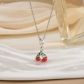 Detail of silver cherry necklace with red enamel pendants on white display stand - Silver Red Cherry with Green Leaf