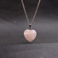 Close-up of heart-shaped pink crystal pendant on a silver chain over a black background - Rose Quartz with Chain