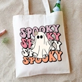 Detail of Spooky ghost print on cream canvas tote bag laid on sand with beach props - Spooky (Ghost)