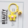 Detail of handmade knitted yellow flower keychain with pink center and matching metal bell - Yellow