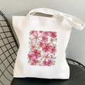 White canvas tote bag featuring pink and white cosmos flower patterns on a black mesh chair - Pink and White Flowers