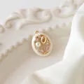 Dettaglio del ciondolo a tulipano dorato con smalto e perla su vassoio vintage bianco - Ciondolo ovale cavo (con perla)