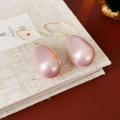 Vista macro di orecchini vintage con perle a goccia rosa e ganci dorati eleganti - Rosa