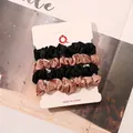 Detail of 4-pack satin scrunchies in black and champagne on a display card - Black and Champagne