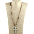 Detail van bohemien gebedsketting met beige kralen en witte kruishanger op een etalagepop - camel