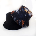 Detail view of foldable reversible bucket hats in solid black and colorful star sky prints - Tie Dye Skull Pattern