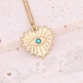 Close-up of golden evil eye heart pendant with blue gemstone on a textured stone - Blue Zircon Heart Eye Style (8#)