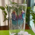 Elegant gradient S925 silver cicada wing drop earrings on a clear glass rim with greenery - Rainbow Silver Foil