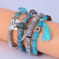 Detail of bohemian multilayer bracelets featuring wing charms, blue tassels and beaded strands - Light Blue