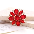Close-up of red marquise crystal flower accessory with golden base on textured stone - Red