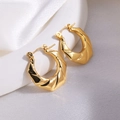 Makroaufnahme goldener Blumenohrringe mit asymmetrischem Design auf weißem Seidenstoff - Gold Geometrisch