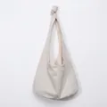 Detail of minimalist cream canvas hobo bag showing the decorative shoulder strap knot - Canvas Beige